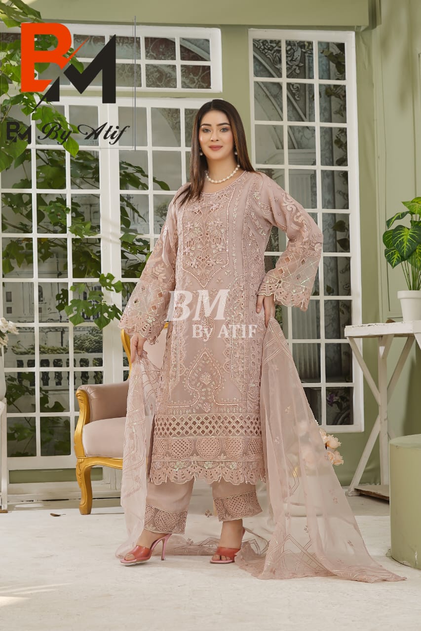 Woman wearing a pink embroidered outfit with 'BM by Alif' branding in an outdoor setting.
